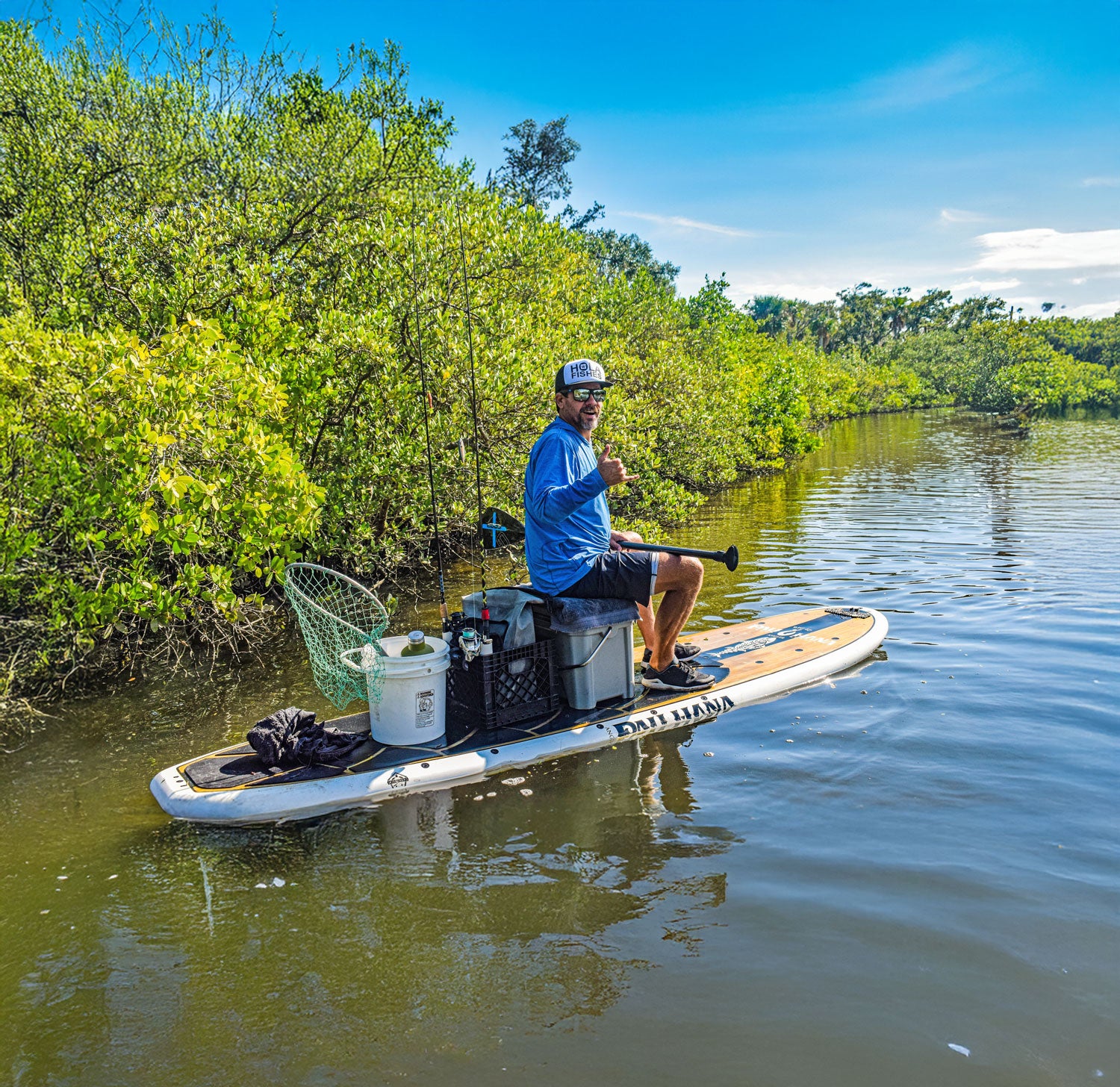 Man on a paddleboard in a natural setting with trees and water.
