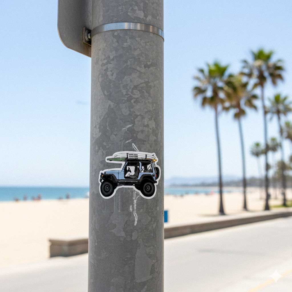 Sticker of a beach scene with a car and surfboard on a lamp post by the ocean.