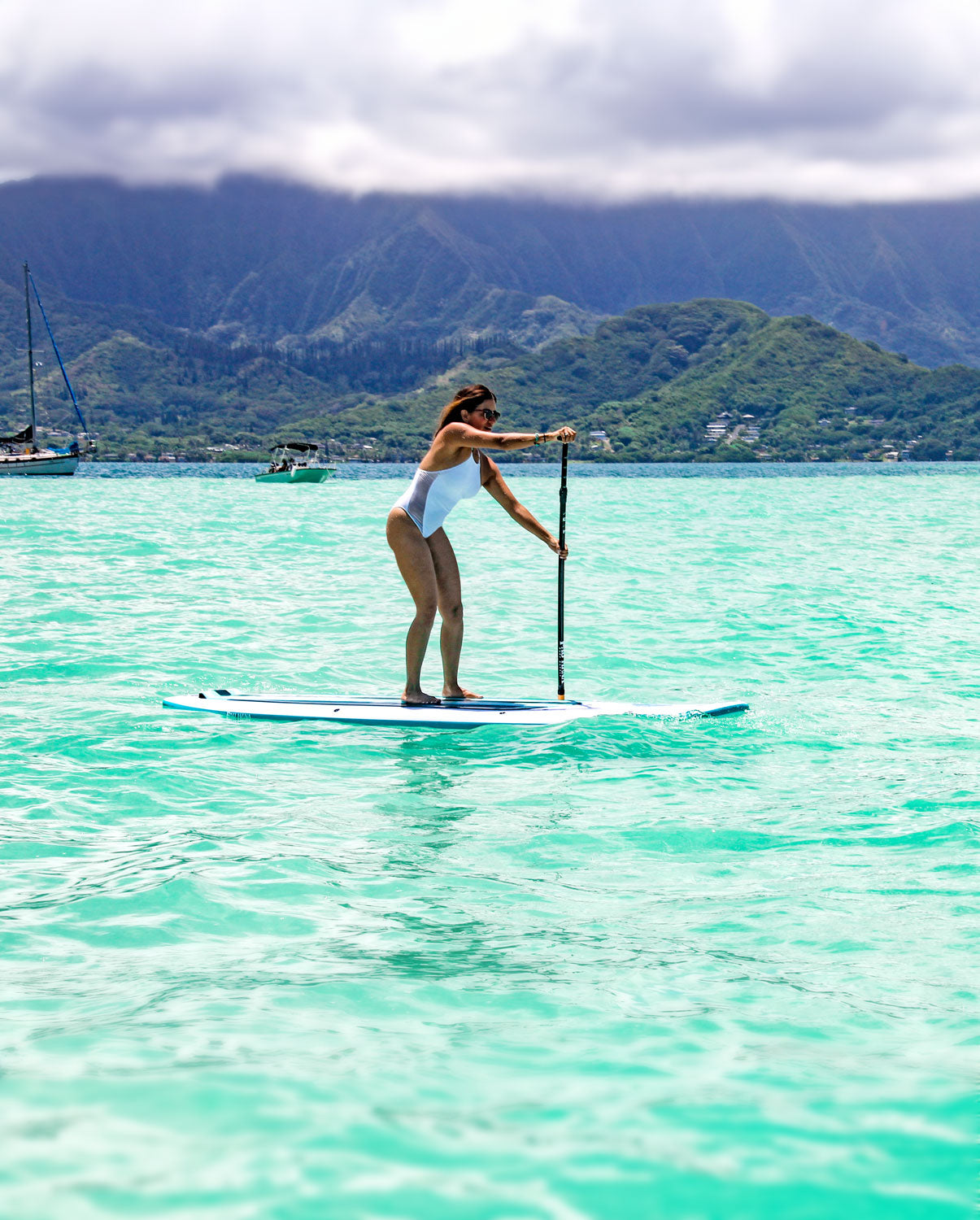 "Pau Hana Surf Supply paddler in Kaneohe Bay, Hawaii, showcasing the stability of the Malibu Classic SUP board on turquoise waters, Ko'olau mountains backdrop"