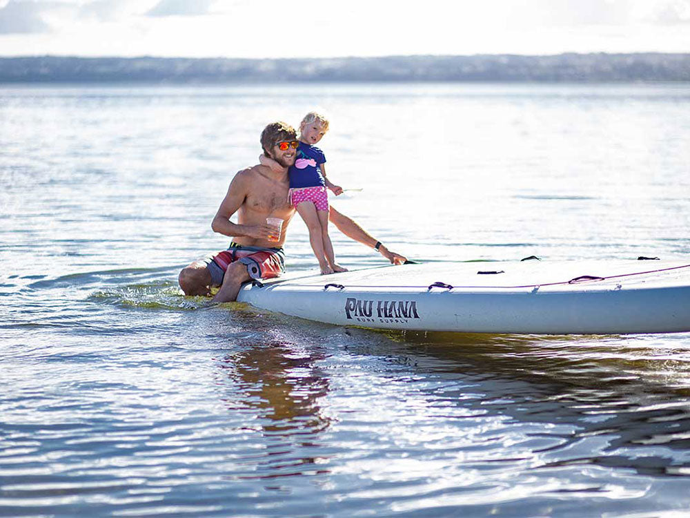 A man and child on the Oahu Nui giant inflatable family paddleboard on a lake in new zealand