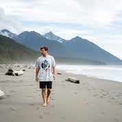Man walking on a beach with mountains in the background