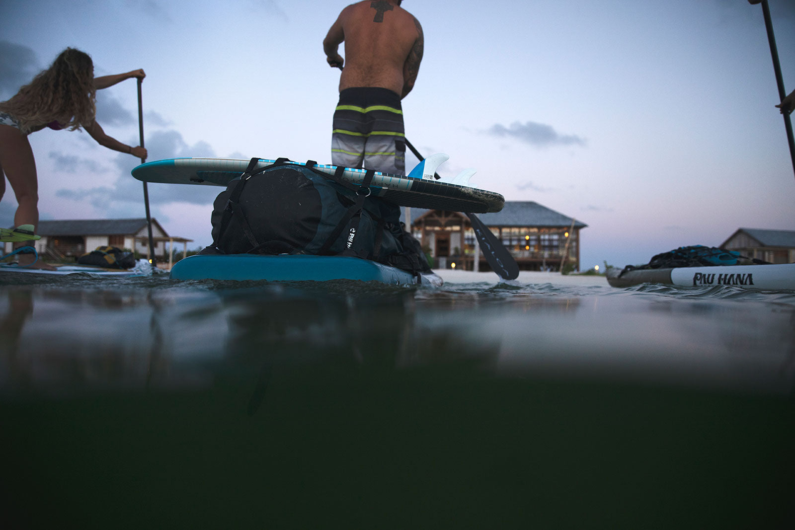 Paddleboarding at sunset in barbuda with kiteboards and drybags attached to the paddleboard