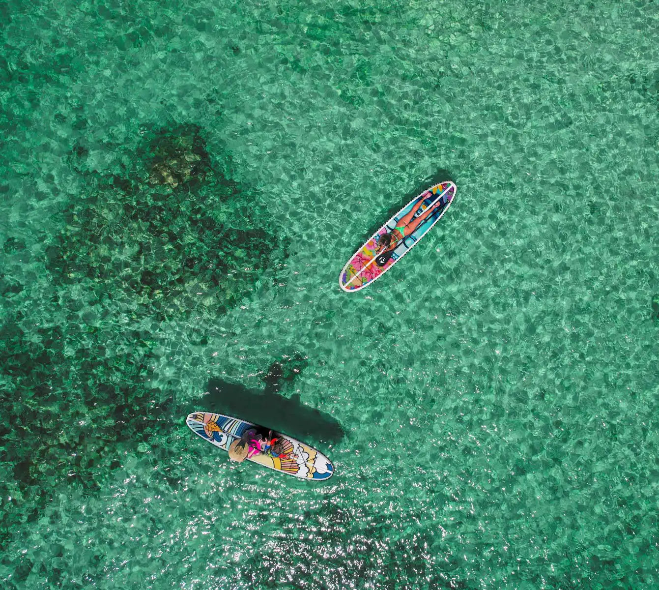 Two colorful paddleboards floating on clear turquoise water.