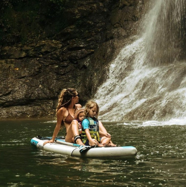 &quot;Pau Hana Surf Supply Solo SUP board carrying family by waterfall, showcasing 10&#39;10&quot; length and 240L volume capacity&quot;